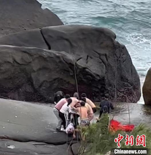 圖為游客在海南文昌石頭公園脫衣擰成長(zhǎng)繩拋下礁石救人現(xiàn)場(chǎng)視頻截圖�！》钊骸z